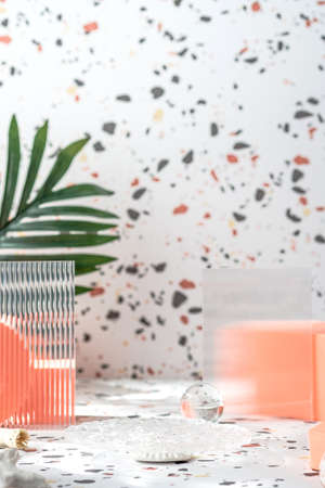 peach geometric pedestal on terrazzo background with summer sunlight and green leafの写真素材