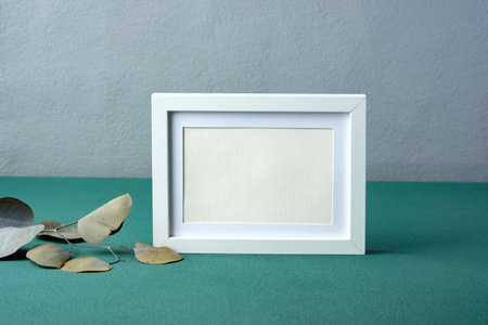 photo frame mockup with eucalyptus branch on green tableの写真素材