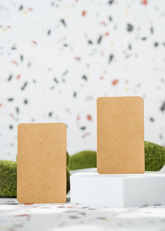 kraft paper on white geometric pedestal on terrazzo background with summer sunlight and moss rockの写真素材