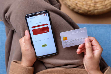 close up woman choose payment online on shopping mobile app on sofa at homeの写真素材