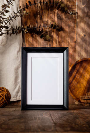 blank black photo frame with kitchenware on wood table with sunlightの写真素材