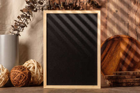 blank blackboard frame with kitchenware on wood table with sunlightの写真素材