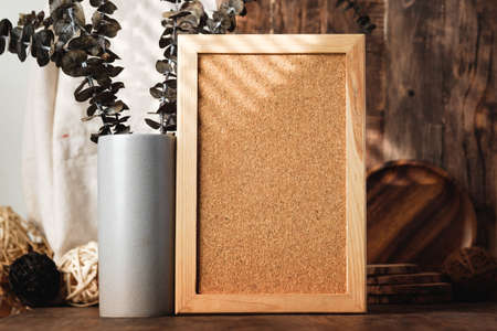 blank corkboard with kitchenware on wood table with sunlightの写真素材