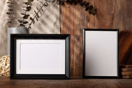 blank black photo frame with kitchenware on wood table with sunlightの写真素材