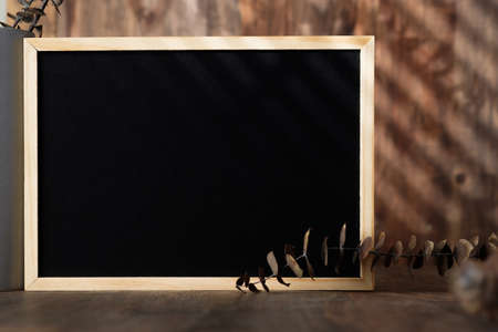 blank blackboard frame with kitchenware on wood table with sunlightの写真素材