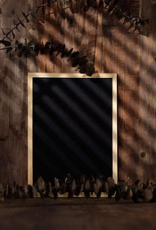blank blackboard frame with kitchenware on wood table with sunlightの写真素材