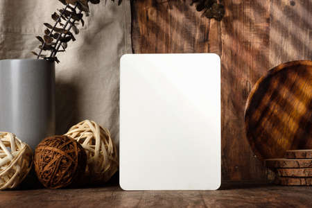 blank paper poster frame with kitchenware on wood table with sunlightの写真素材