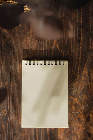 blank sprial notebook with wicker bag and travel stuff on table with sunlight