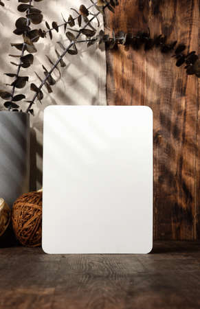 blank paper poster frame with kitchenware on wood table with sunlightの写真素材