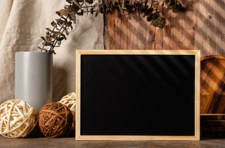 blank blackboard frame with kitchenware on wood table with sunlightの写真素材