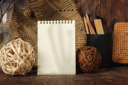 blank sprial notebook with wicker bag and travel stuff on table with sunlightの写真素材