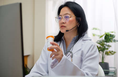 asian woman doctor visit patient video call online diagnose symptom at clinicの写真素材