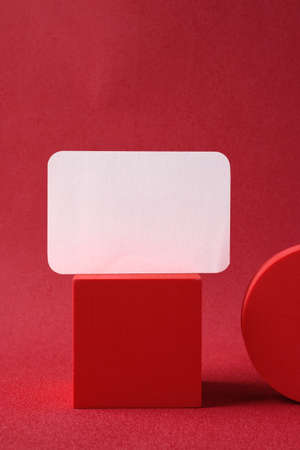 blank business card on pedestal on vivid red background studioの写真素材