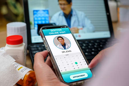 asian woman appointment consulting doctor visit on mobile app at home.telemedicineの写真素材