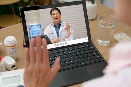 asian woman telemedicine doctor online visit with computer at homeの写真素材
