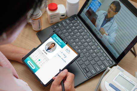 asian woman appointment consulting doctor visit on mobile app at home.telemedicineの写真素材