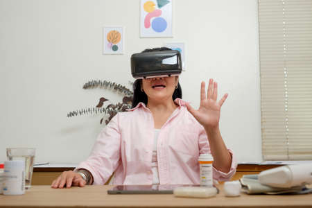 asian woman telemedicine doctor online visit with virtual reality technology vr glasses at homeの写真素材