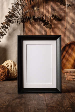 blank black photo frame with kitchenware on wood table with sunlightの写真素材