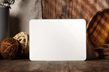 blank paper poster frame with kitchenware on wood table with sunlightの写真素材