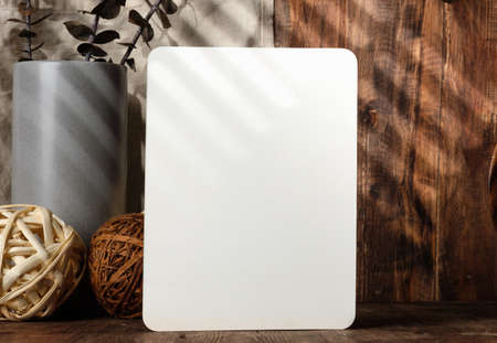 blank paper poster frame with kitchenware on wood table with sunlightの写真素材