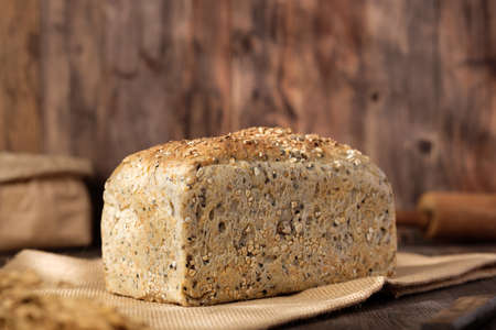 whole wheat baking bread with grains for healthy eating on wood table in kitchenの写真素材