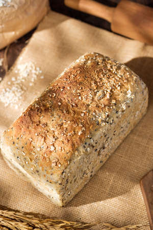 whole wheat baking bread with grains for healthy eating on wood table in kitchenの写真素材
