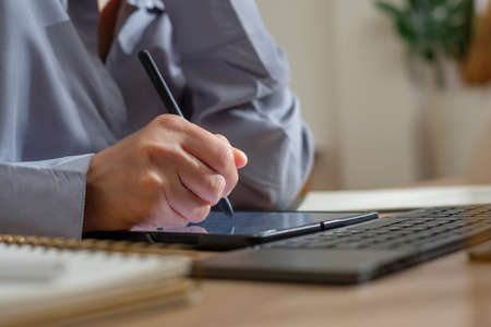 asian woman use mobile while video conference meeting online with tablet at homeの写真素材