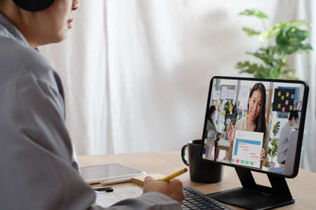asian woman video conference business meeting with colleage online with tablet at homeの写真素材