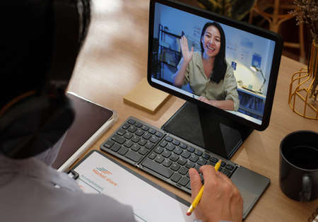 asian woman video conference business meeting with colleage online with tablet at homeの写真素材