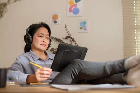 asian woman cross leg on table planning busines goal using tablet at homeの写真素材