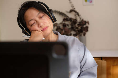asian woman feel bored when video conference meeting at homeの写真素材
