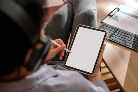 close up woman cross leg on table writing business plan using tablet at home