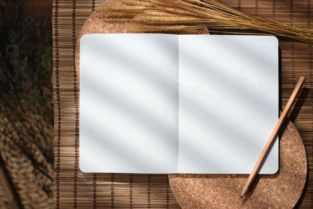 mockup open blank notebook on brown mat with sunlightの写真素材