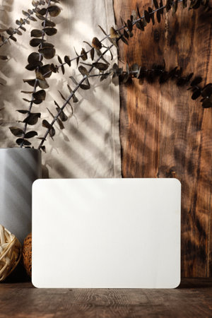 blank paper poster frame with kitchenware on wood table with sunlightの写真素材