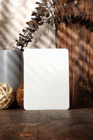 blank paper poster frame with kitchenware on wood table with sunlightの写真素材