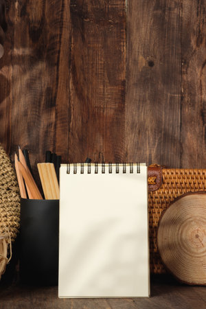 blank sprial notebook with wicker bag and travel stuff on table with sunlightの写真素材