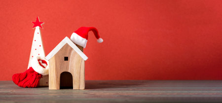 Merry chistmas and happy new year with wooden home wear santa hat on wood table with vivid red backgroundの写真素材