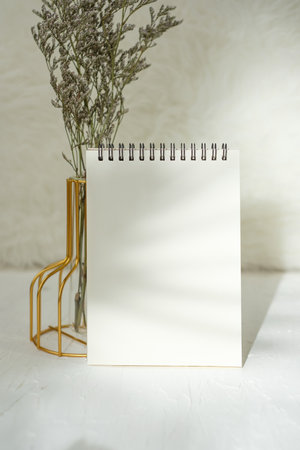 mockup notebook with flower in vase on white stone tableの写真素材