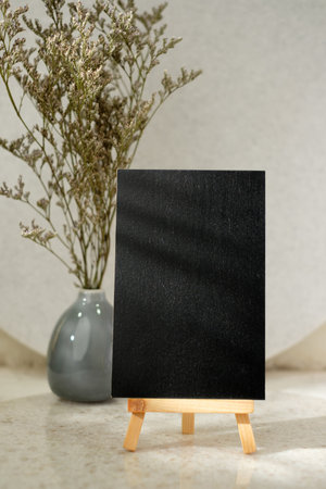mockup blank blackboard with easel card with flower in vase on white stone tableの写真素材