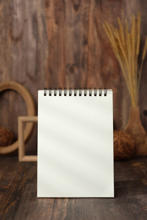 mockup blank spiral notebook with wood photo frame and wicker ball on tableの写真素材