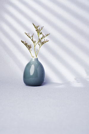 flower in ceramic grey vase with window sunlight on soft pastel violet color backgroundの写真素材