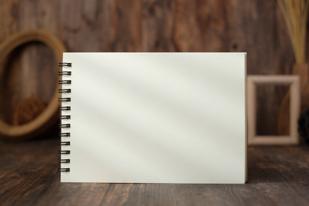 mockup blank spiral notebook with wood photo frame and wicker ball on tableの写真素材
