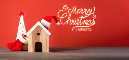 Merry chistmas and happy new year with wooden home wear santa hat on wood table with vivid red backgroundの写真素材