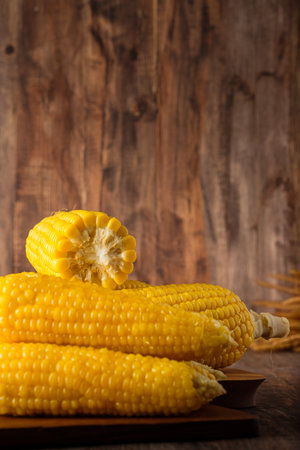 Group of corn cob in tray on wood tabele and wallの写真素材