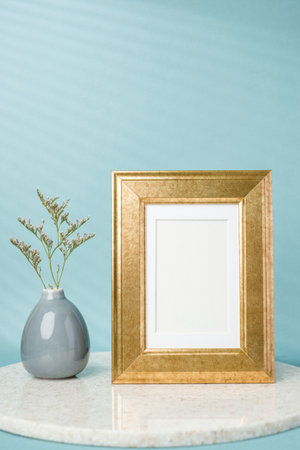 blank luxury gold photo frame with flower vase decor on stone table wtih blue backgroundの写真素材