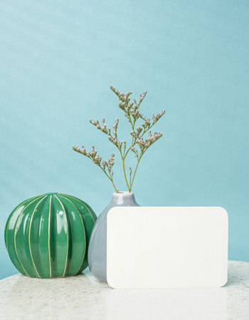 blank poster paper card with flower vase and cactus decor on stone table wtih blue backgroundの写真素材