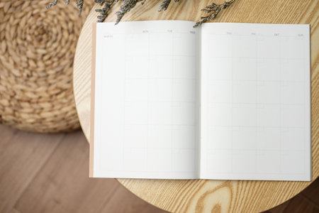 open blank calendar planner notebook with pen on wood table with sunlight