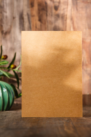 Blank Kraft card paper with botanical plant with sunlight at wood table and wallの写真素材