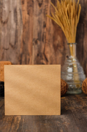 mockup square kraft paper card on wood table and decor with wicker decoration items.の写真素材