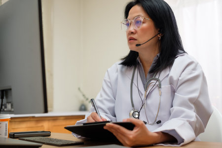 asian woman doctor visit patient video call online diagnose symptom at clinicの写真素材